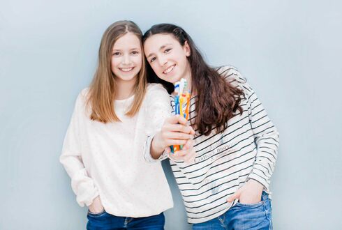 Mädchen halten Zahnbürste und Zahnpasta hoch